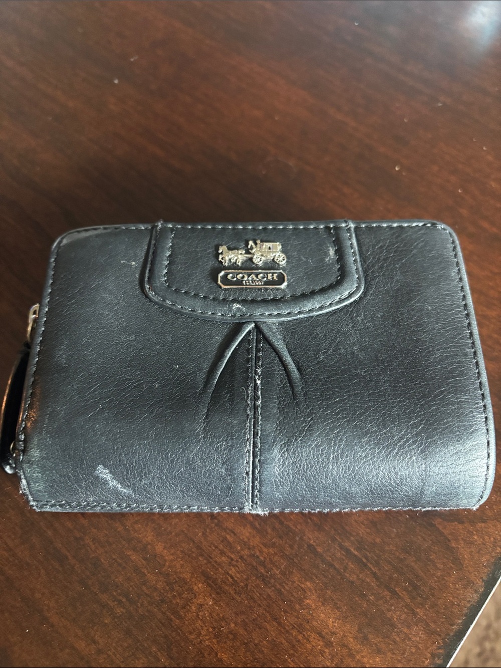 Coach Madison bifold wallet featuring the iconic horse and carriage logo plaque